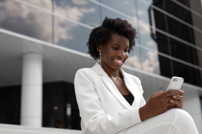 a woman in a white suit looking at her cell phone
