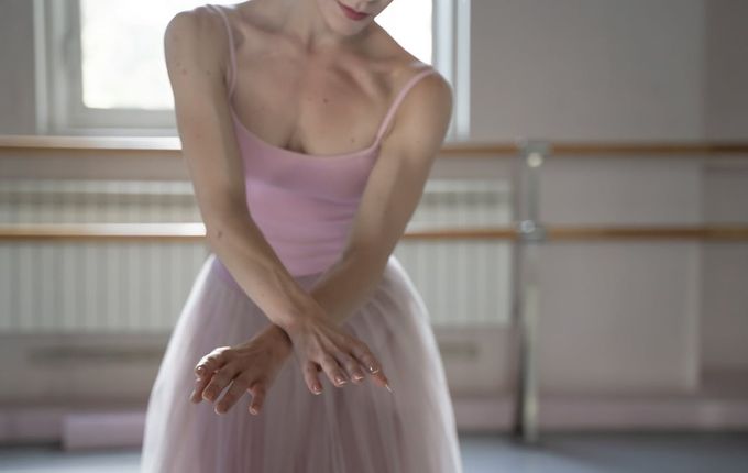 a woman in a pink dress standing in front of a window