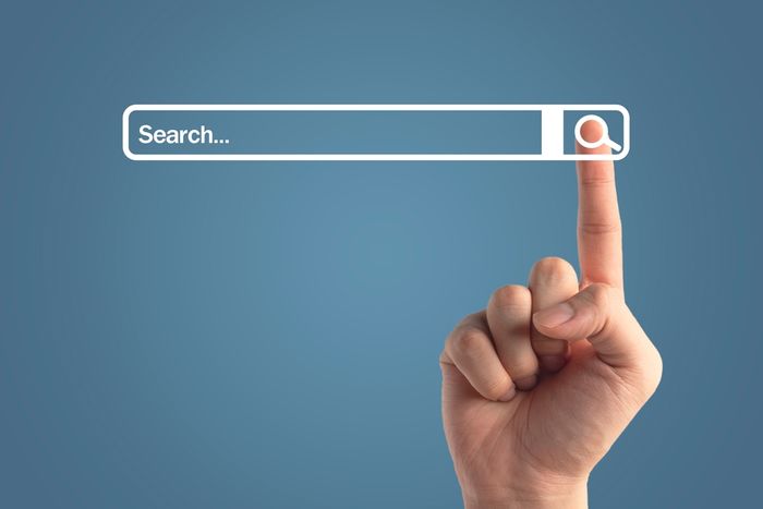 a hand pushing a button on a search bar