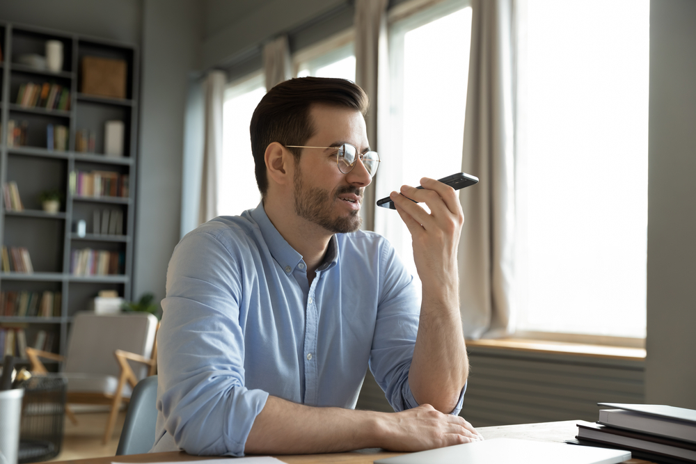 a man sitting at a desk holding a cell phone